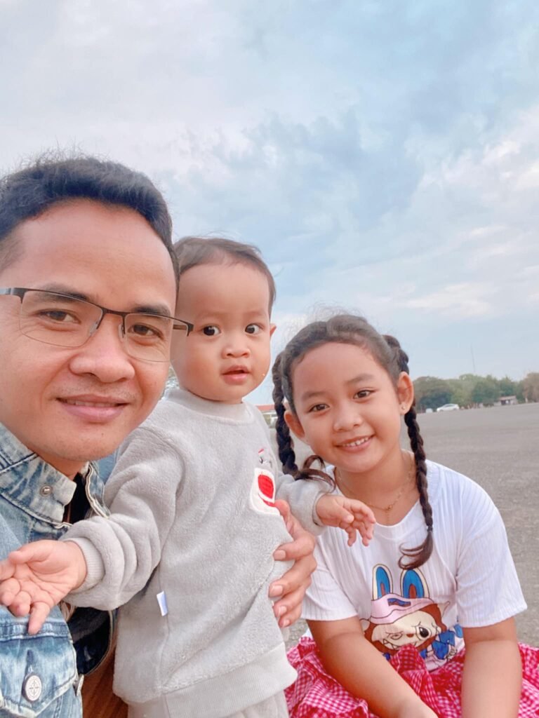 Noeum, The Professor Dad, smiling with his 8-year-old daughter and 2-year-old son outdoors.