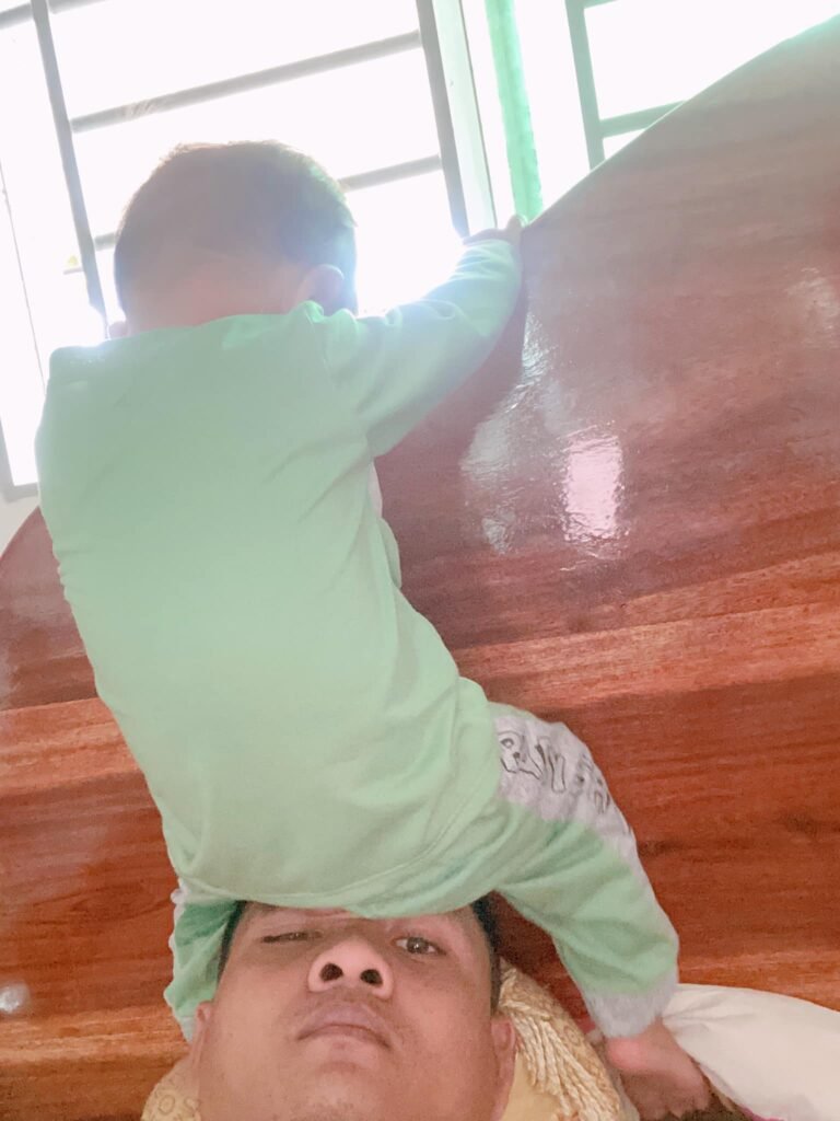 Toddler son climbing on top of his father's head while playing indoors.