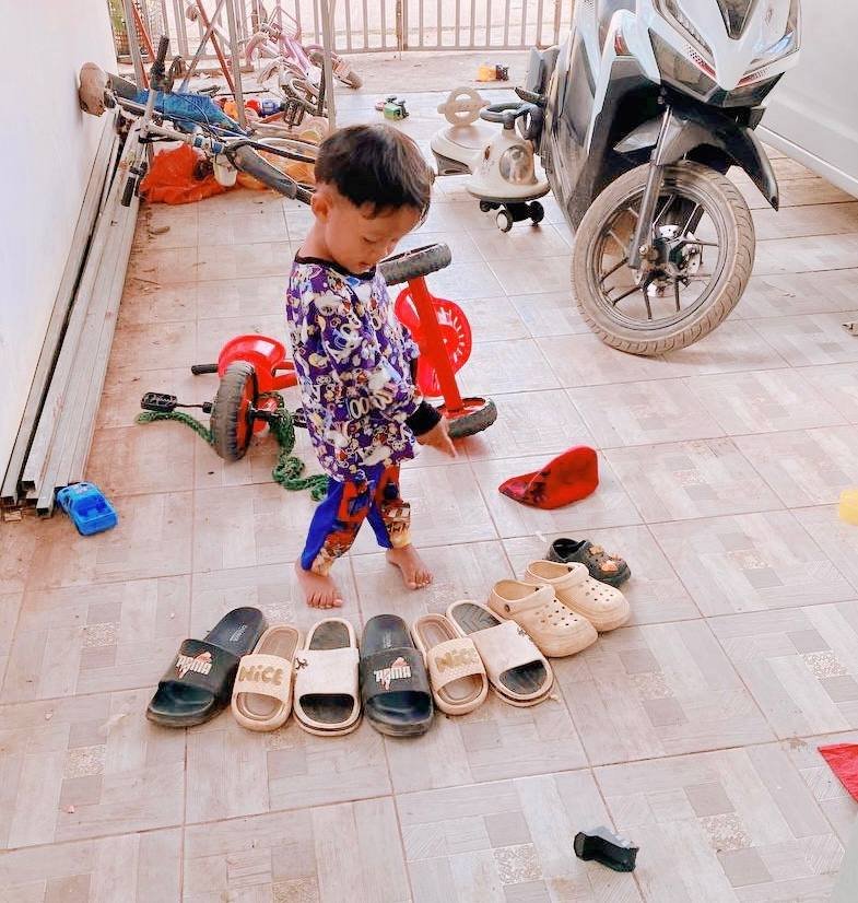 A row of mixed footwear including black slides with the word NICE printed on them in gold letters.