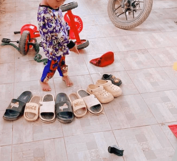 A row of mixed footwear including black slides with the word NICE printed on them in gold letters.