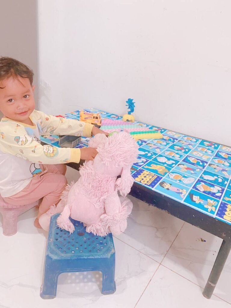 Happy toddler boy smiling at the camera after a lesson on sharing toys and cooperative play.