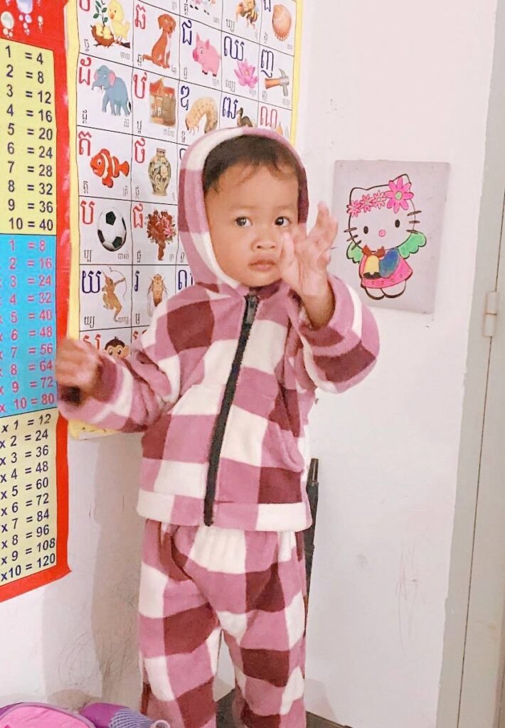 A young child reaching out towards a number chart, showing how to use hand gestures to learn numbers without flashcards.