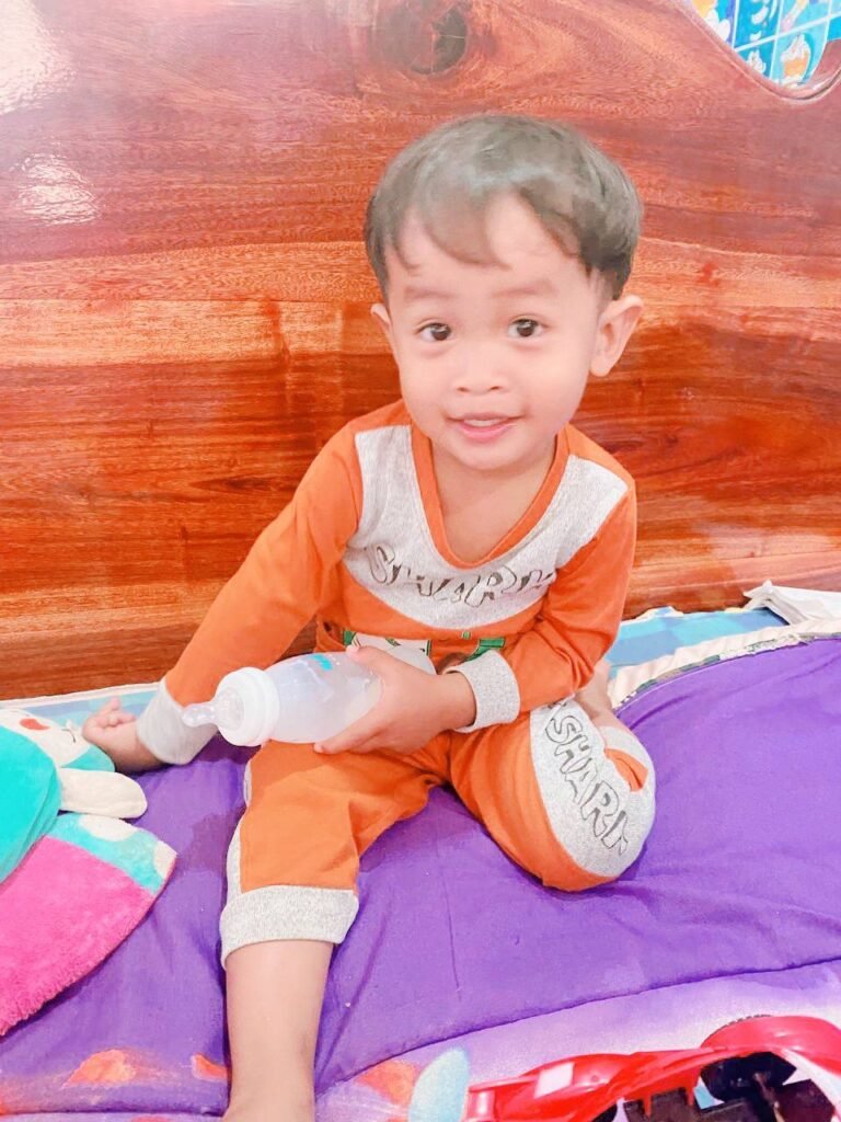 Happy toddler holding a milk bottle and smiling because he feels safe in his favorite clothes.
