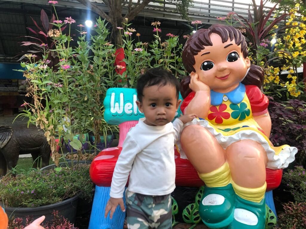 Close up of toddler looking upset and confused while standing next to a garden statue.