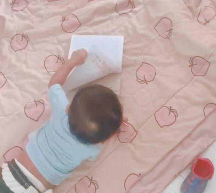 Toddler flipping the page of a lined notebook, practicing fine motor skills and book sequencing.