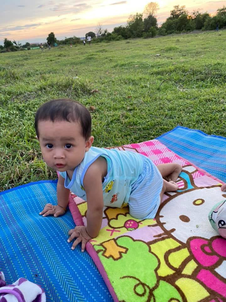 A two-year-old boy exploring the grass while sitting on a Hello Kitty picnic mat during a family microadventure.