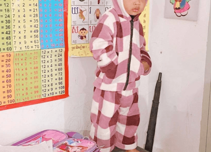 A toddler standing next to a multiplication chart on the wall, illustrating environmental learning for early math skills.