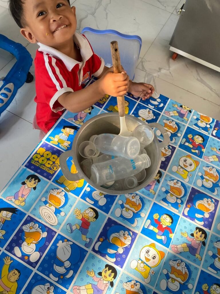 Close up of an aluminum pot filled with empty plastic milk bottles and lids for a pretend cooking activity.