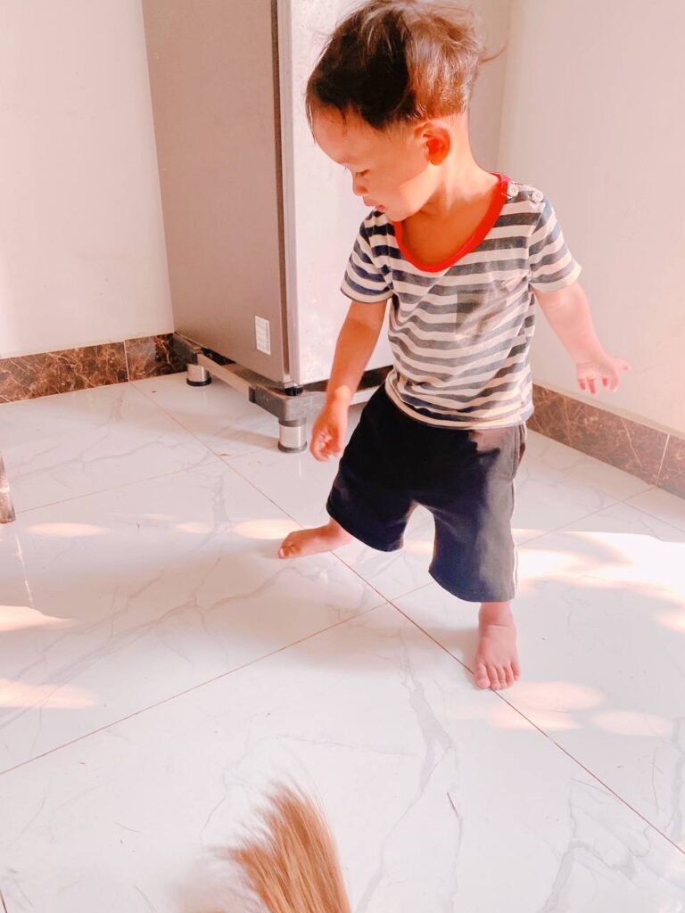 Two-year-old boy walking into the kitchen in the morning wearing a striped shirt.