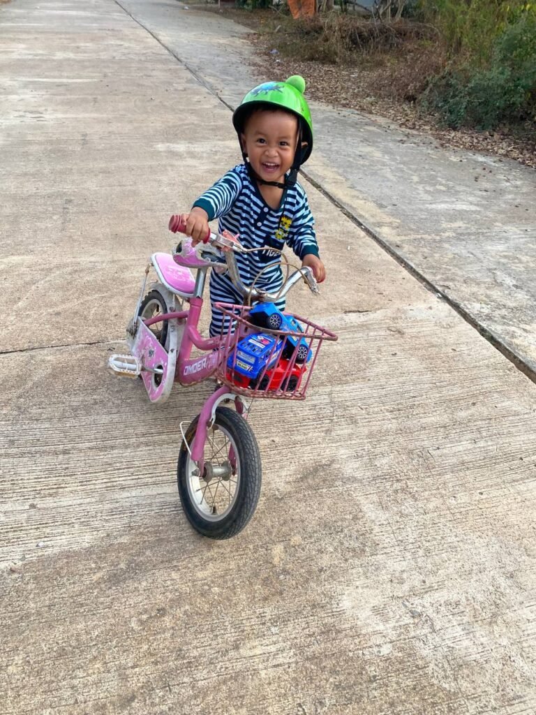 A toddler smiling while riding a pink bicycle, illustrating a successful change management strategy where the user feels in control.