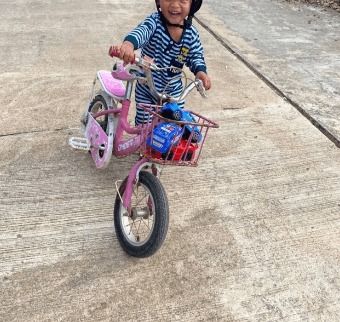 A toddler smiling while riding a pink bicycle, illustrating a successful change management strategy where the user feels in control.