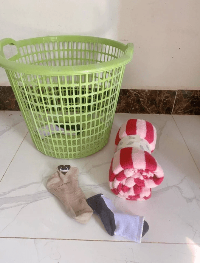 A green plastic laundry basket next to rolled-up socks and a small blanket used for safe indoor throwing games.