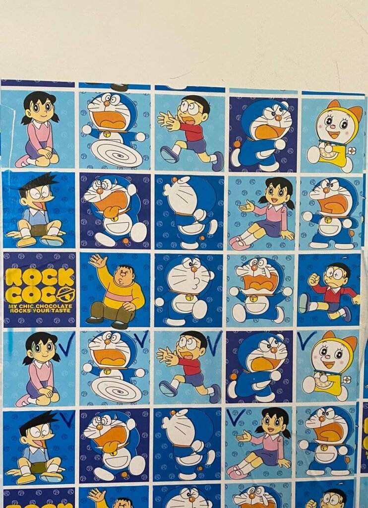 Close up of blue Doraemon patterned paper used to cover a child's study desk surface and the surrounding wall.