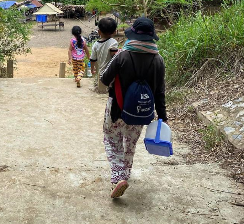 A mother and two young children walk down concrete outdoor steps carrying a bucket and backpack for a local nature microadventure.