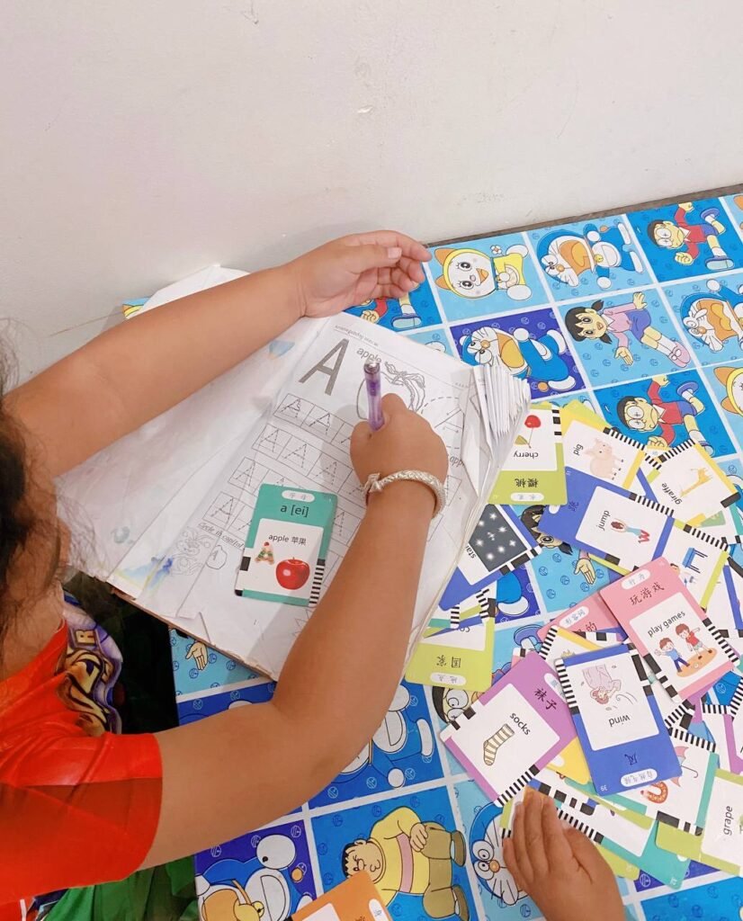 Child placing an apple flashcard onto a workbook page for the letter A to match the starting sound.