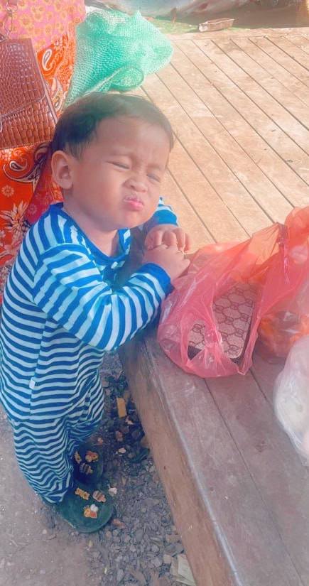 Toddler boy making a funny scrunched-up face and leaning on elbows in a silent protest.