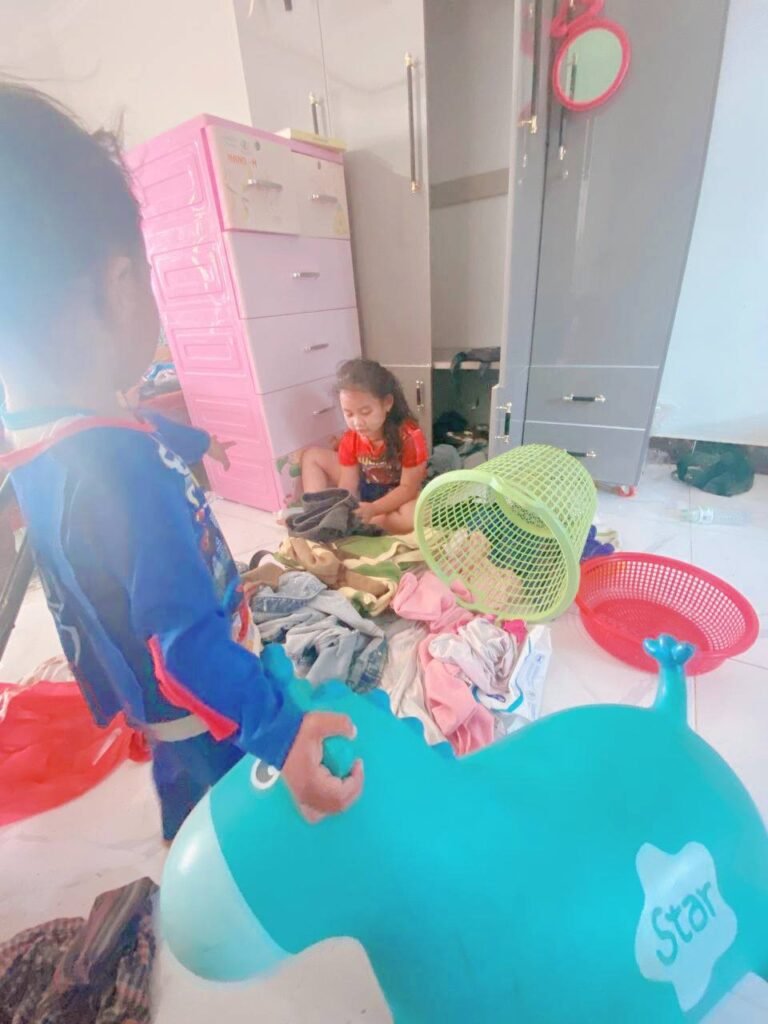 A messy bedroom floor covered in clothes and a blue bouncy horse toy, illustrating parenting struggles with chores.