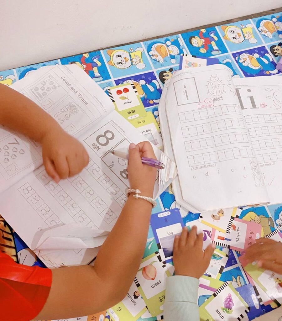 Overhead view of a 2nd grader doing a phonics activity with a Count and Trace workbook and scattered flashcards on a table.