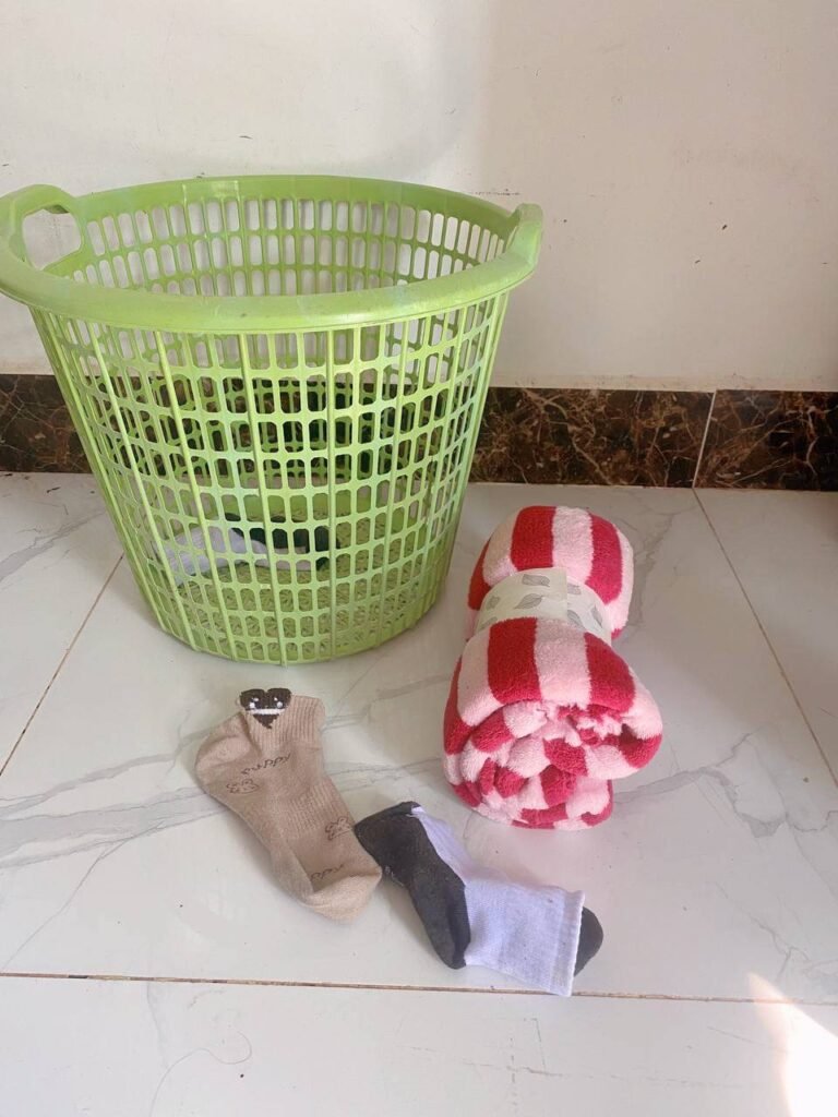 Green laundry basket, rolled up socks, and soft towel for a toddler indoor throwing activity.