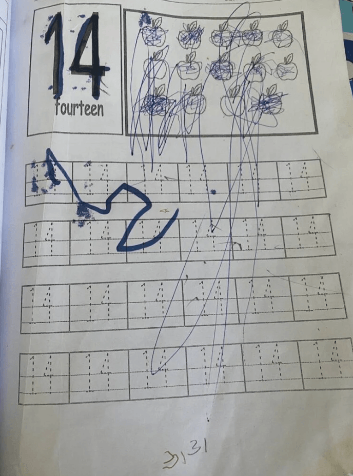 A workbook page practicing the number 14 covered in frustrated, heavy blue scribbles.
