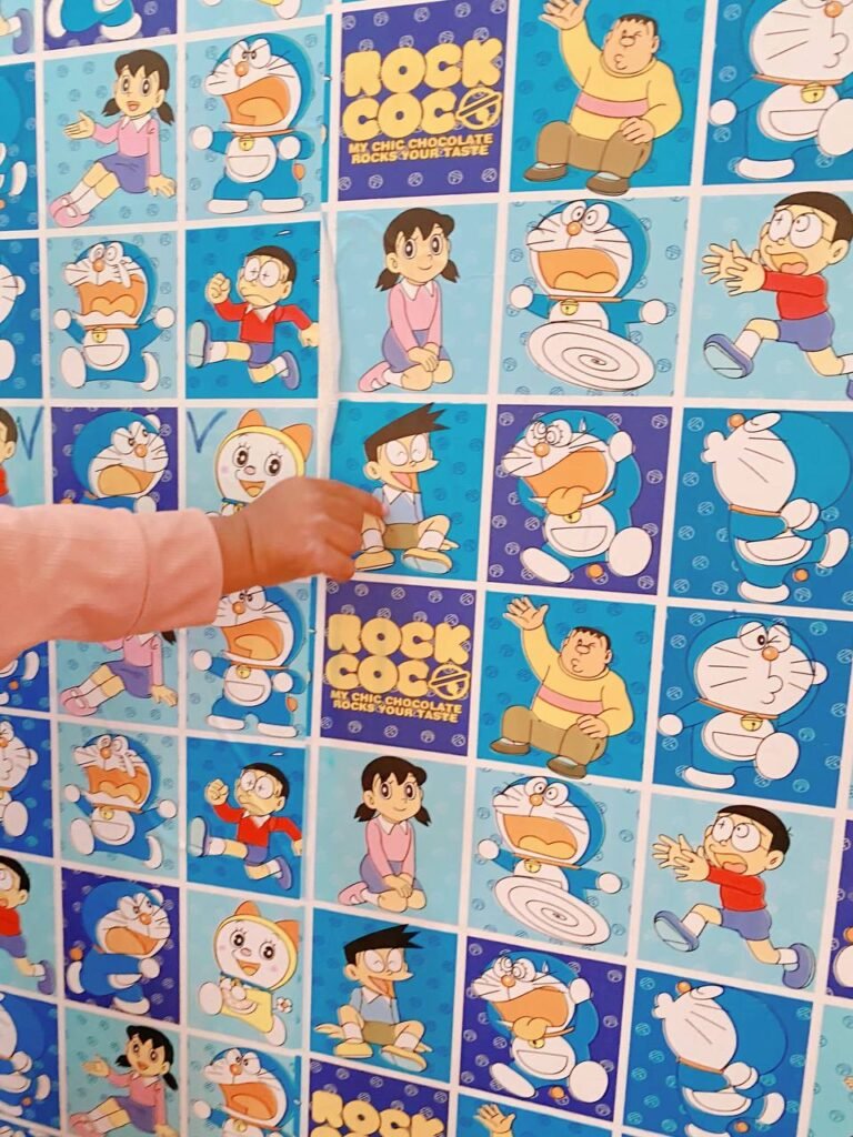 A toddler's hand pointing to a smiling cartoon character on a wall, used as a visual cue for handling difficult moments.