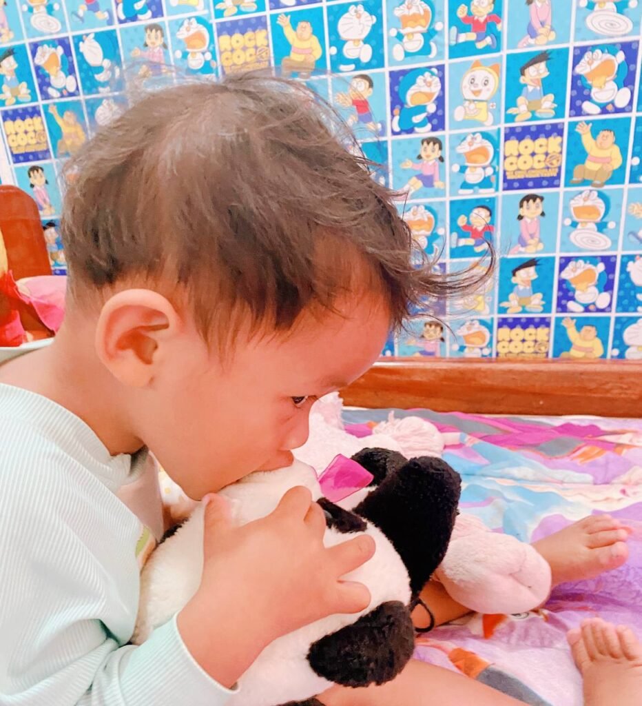 Toddler biting a stuffed panda bear toy as a safe alternative to biting people.