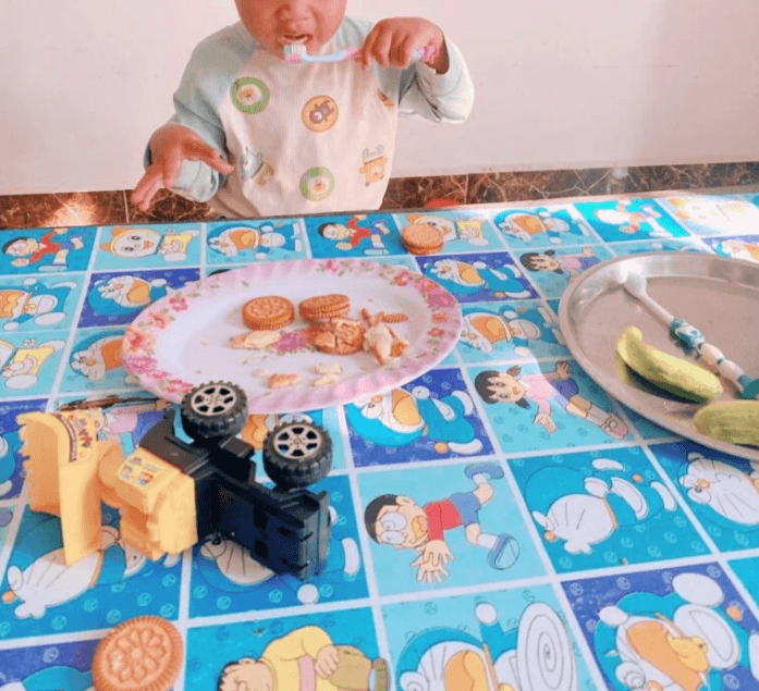 Toddler holding a soft toothbrush and eating cucumbers on a plate to relieve sore gums.