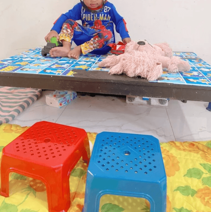 Red and blue plastic step stools and a low coffee table set up for an indoor obstacle course.