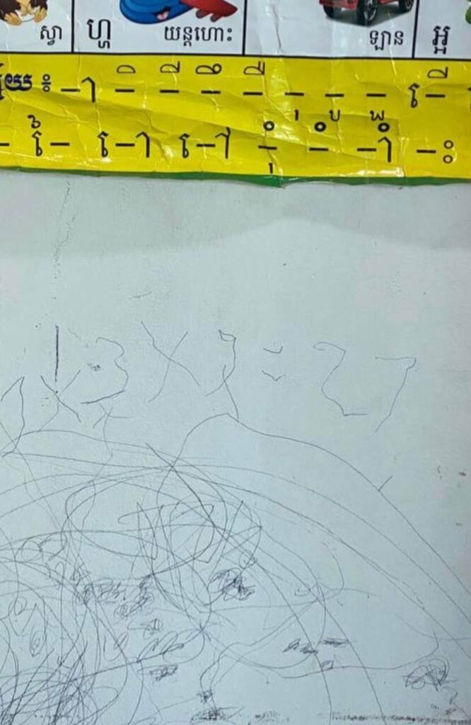 A close-up view of blue ink scribbles on a wall with the math multiplication problem 3 x 9 = 27 written in the center.