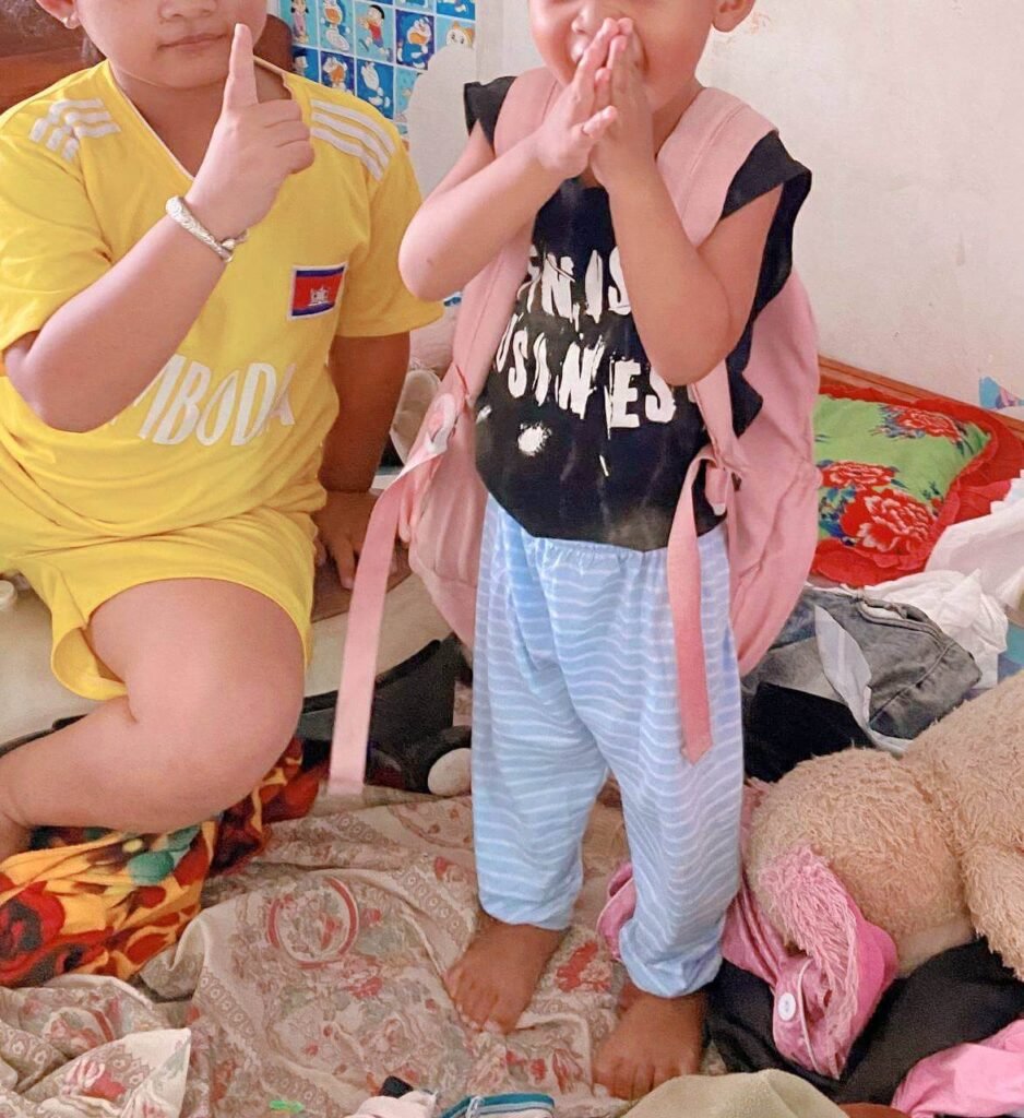 Older sister holding up a finger to instruct her toddler brother about respect, while he presses his hands together in a gentle bow.