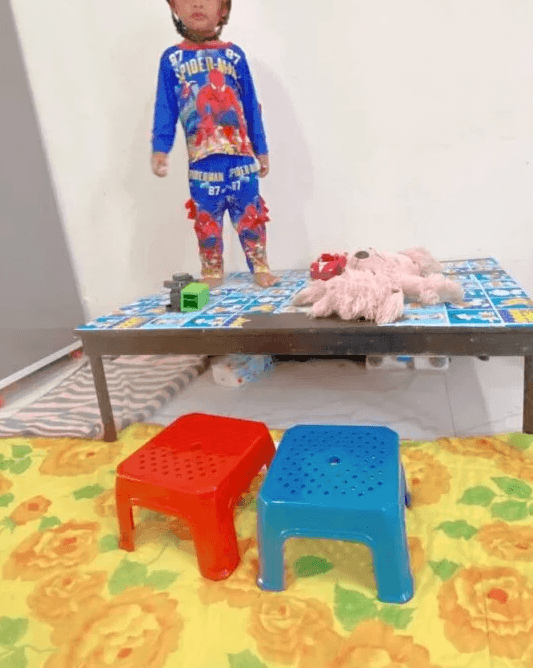 Toddler standing happily on top of a coffee table after completing the obstacle course.